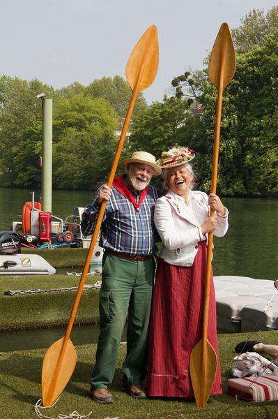 Un homme au canotier et une Dame costumée 1900 posent avec deux pagayes verticales